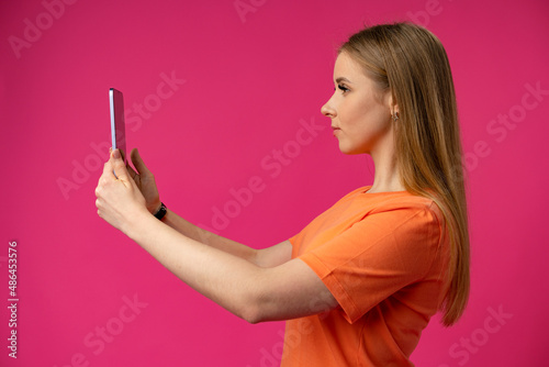 Portrait of a young woman using mobile phone over color background.