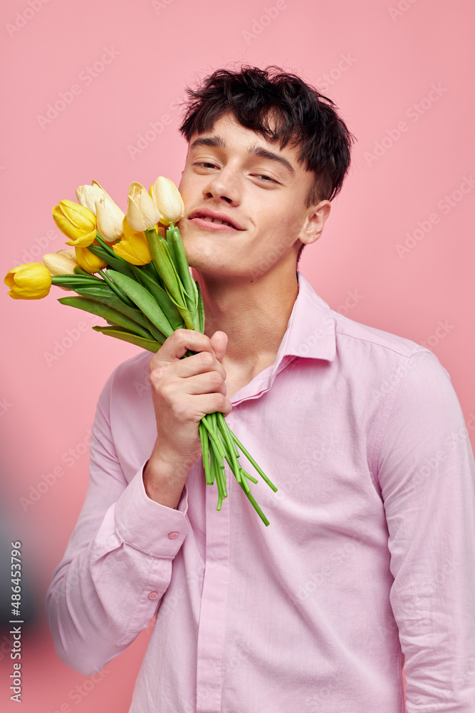 A young man Bouquet of yellow flowers romance posing fashion pink background unaltered A young man Bouquet of yellow flowers romance posing fashion pink background unaltered