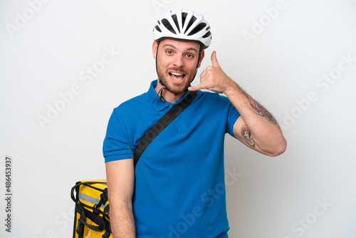 Young brazilian man with thermal backpack isolated on white background making phone gesture. Call me back sign