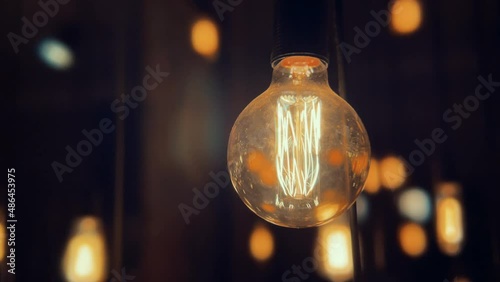Flickering old fashion tungsten Edison light bulb lamp over black background. Slow motion shot 4K.