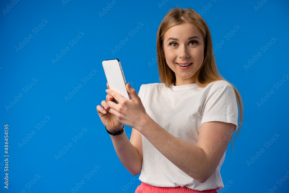 Excited surprised young woman using mobile phone against studio background Excited surprised young woman using mobile phone against studio background