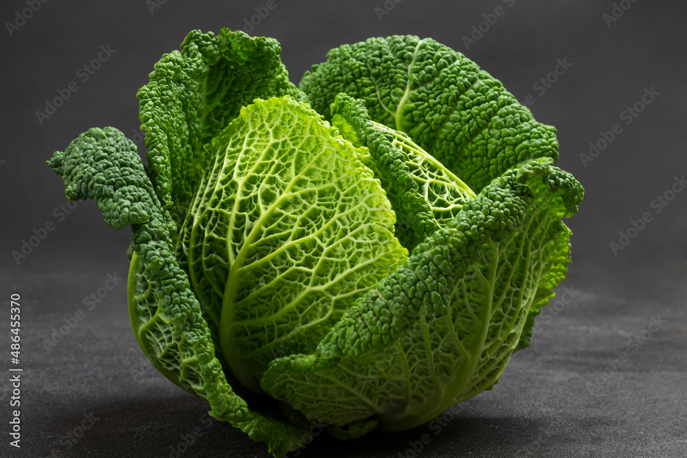 Obraz premium Green Savoy cabbage close up on black. Top view.