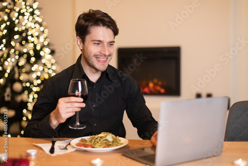 Excited guy having dinner during virtual date on laptop
