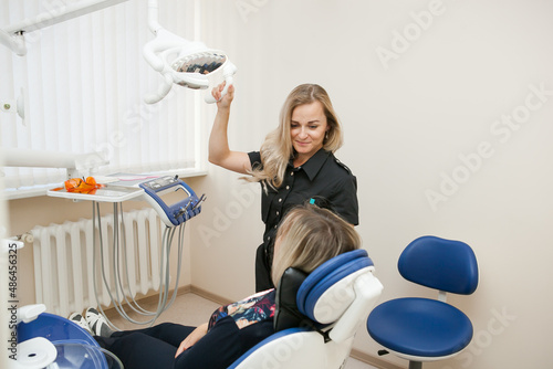 a dentist is a young white woman with blonde hair who is receiving a patient in a dental chair