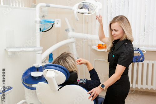 a dentist is a young white woman with blonde hair who is receiving a patient in a dental chair