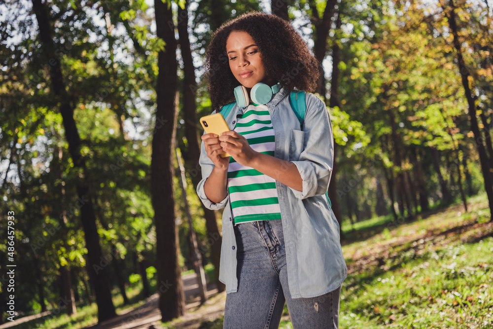 Photo of youth attractive african lady use mobile post comment like influencer green trees backpack outdoors Photo of youth attractive african lady use mobile post comment like influencer green trees backpack outdoors