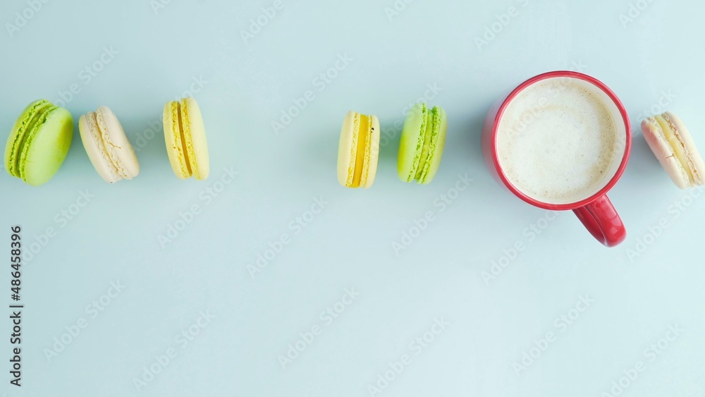 Top view of multicolored French Macarons cookies and a cup of coffee on a pastel blue background Top view of multicolored French Macarons cookies and a cup of coffee on a pastel blue background
