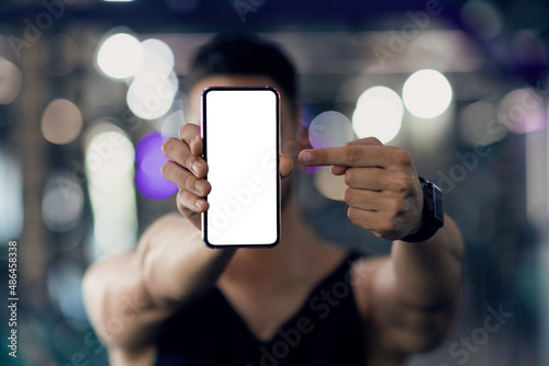 Unrecognizable Male Athlete Holding And Pointing At Blank Smartphone, Recommending Fitness App