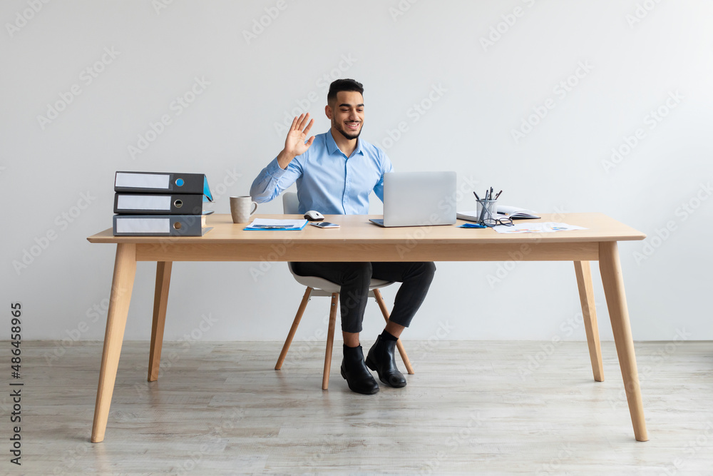 Arab man using laptop waving hand making video call Arab man using laptop waving hand making video call