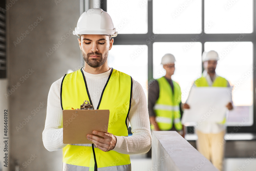 architecture, construction business and building concept - male architect in helmet and safety west with clipboard working at office