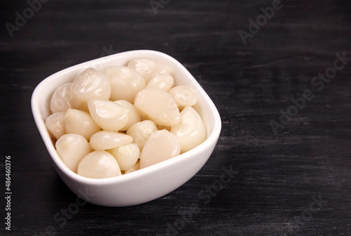 Tasty pickled garlic in the bowl. Canned garlic.