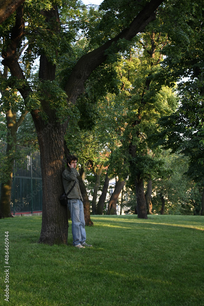 A man stands by a tree and talks on the phone A man stands by a tree and talks on the phone