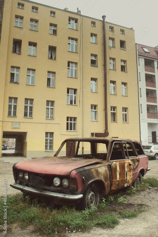 Abandoned, burned car in Western European city, wide shot