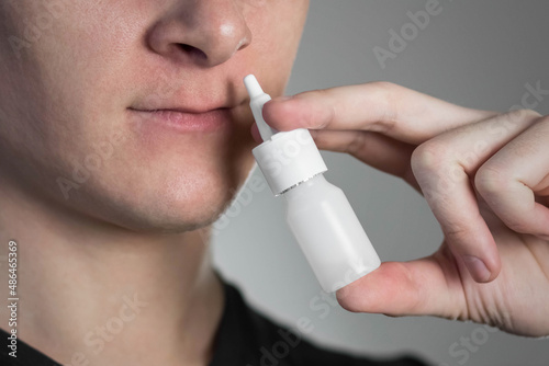 A man sprays a spray into his nose for a runny nose. Close up