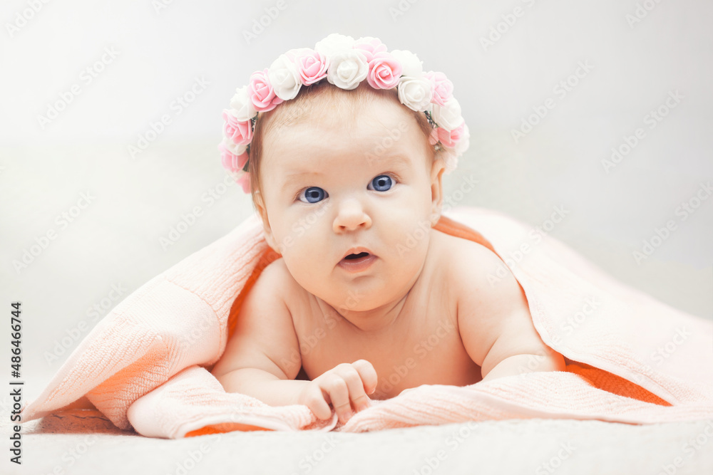 Cute baby with flower wreath. three month old blue-eyed girl wrapped in a terry towel Cute baby with flower wreath. three month old blue-eyed girl wrapped in a terry towel