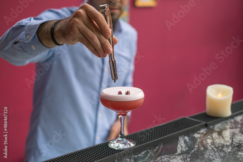 Bartender makes pink cocktail with foam in mister glass. Close up photo, process, bar, decorating. High quality photo
