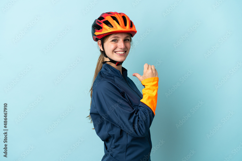 Young cyclist woman isolated on blue background proud and self-satisfied - obrazy, fototapety, plakaty 