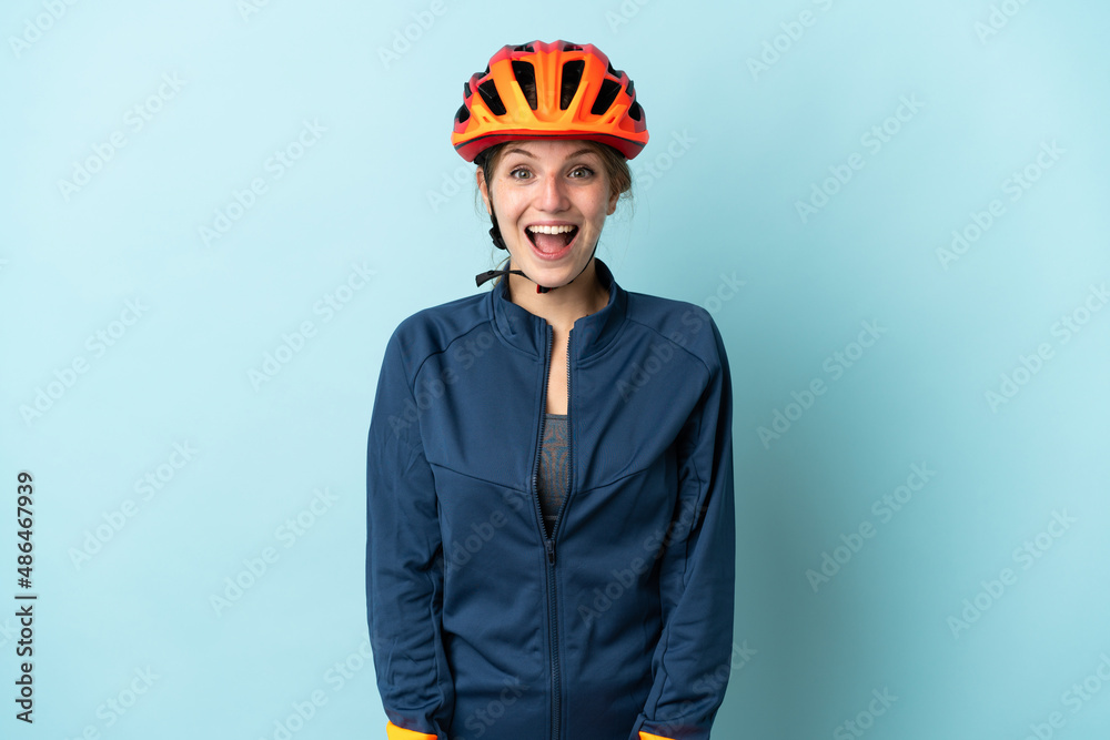 Young cyclist woman isolated on blue background with surprise facial expression - obrazy, fototapety, plakaty 