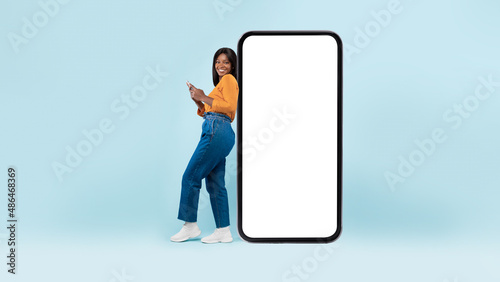 Photos Black woman leaning on white empty smartphone screen, using cellphone