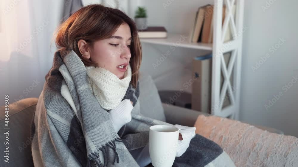 Fever cold. Sick woman. Virus infection. Suffering lady wrapped plaid sitting sofa shivering drinking tea in light room interior. Fever cold. Sick woman. Virus infection. Suffering lady wrapped plaid sitting sofa shivering drinking tea in light room interior.