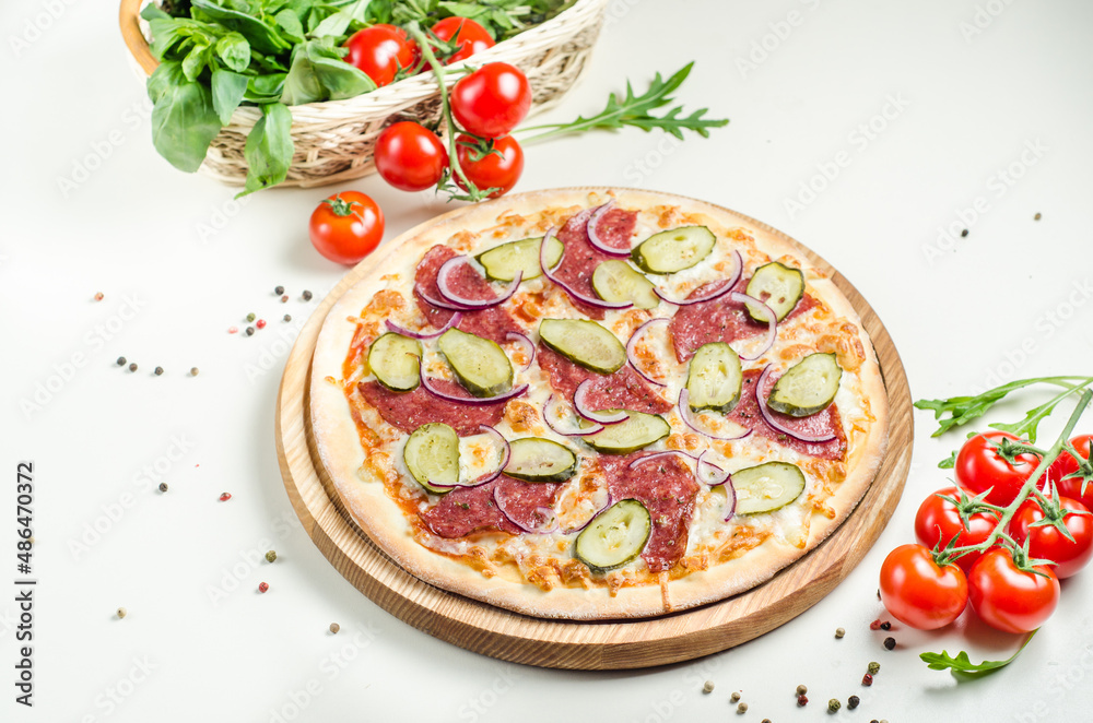 Homemade pizza with sausage, pickles, red onion and cheese on white table. Tasty food
