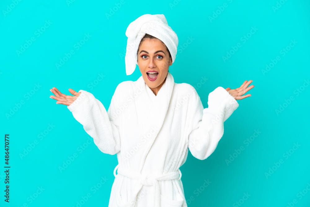 Young woman in a bathrobe over isolated blue background with shocked facial expression Young woman in a bathrobe over isolated blue background with shocked facial expression