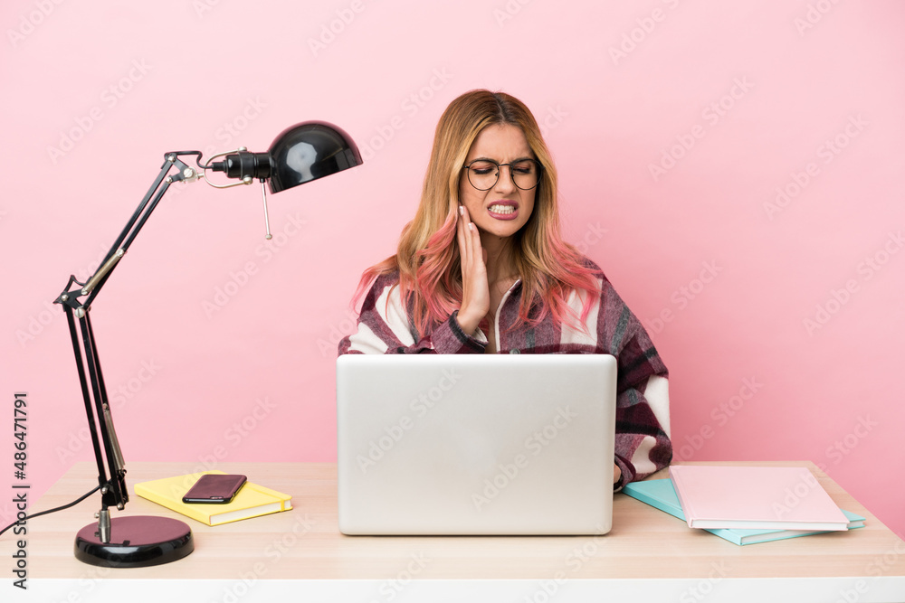Young student woman in a workplace with a laptop over pink background with toothache Young student woman in a workplace with a laptop over pink background with toothache