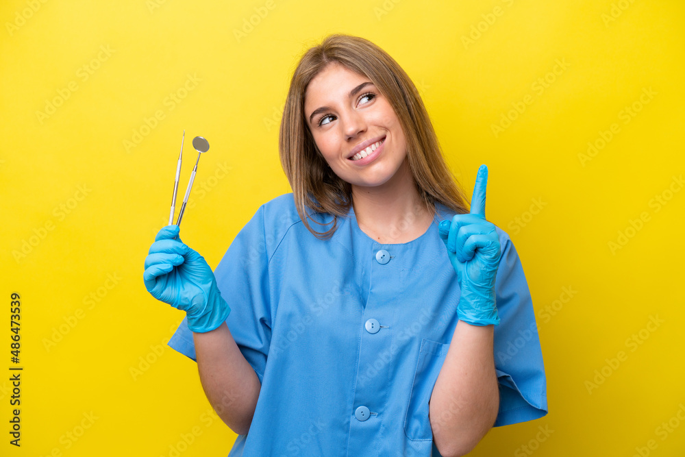 Dentist caucasian woman holding tools isolated on yellow background pointing up a great idea Dentist caucasian woman holding tools isolated on yellow background pointing up a great idea
