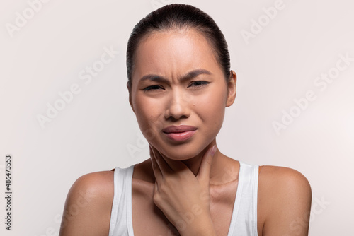 Unhealthy chinese lady touching her neck, closeup