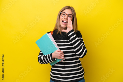 Young student woman isolated on yellow background background shouting with mouth wide open