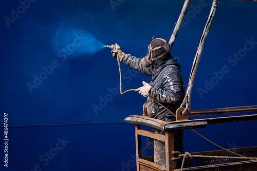 Painters painting a ship at a shipyard