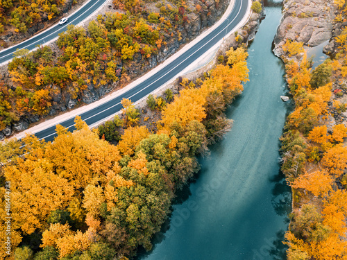 Aerial panoramic view of Venetikos river and serpentine highway road in autumn forest in Balkan Greece. Nature park background
