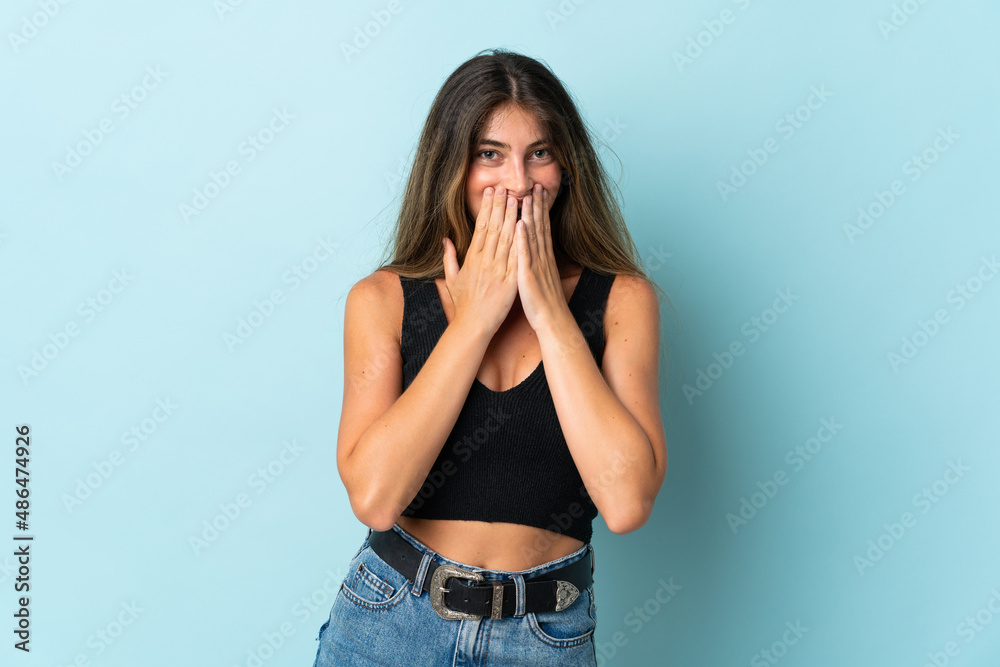 Young caucasian woman isolated on blue background happy and smiling covering mouth with hands Young caucasian woman isolated on blue background happy and smiling covering mouth with hands