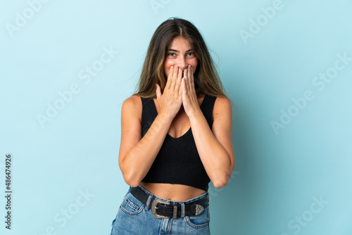 Young caucasian woman isolated on blue background happy and smiling covering mouth with hands