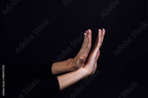Crossed hands of person on black background showing stop sign. Domestic physical, psychological abuse, relative aggression and gaslighting. Copy space.