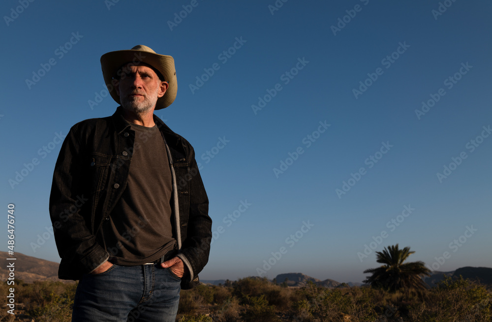 Adult man in cowboy hat on Tabernas desert during sunset. Almeria, Spain Adult man in cowboy hat on Tabernas desert during sunset. Almeria, Spain