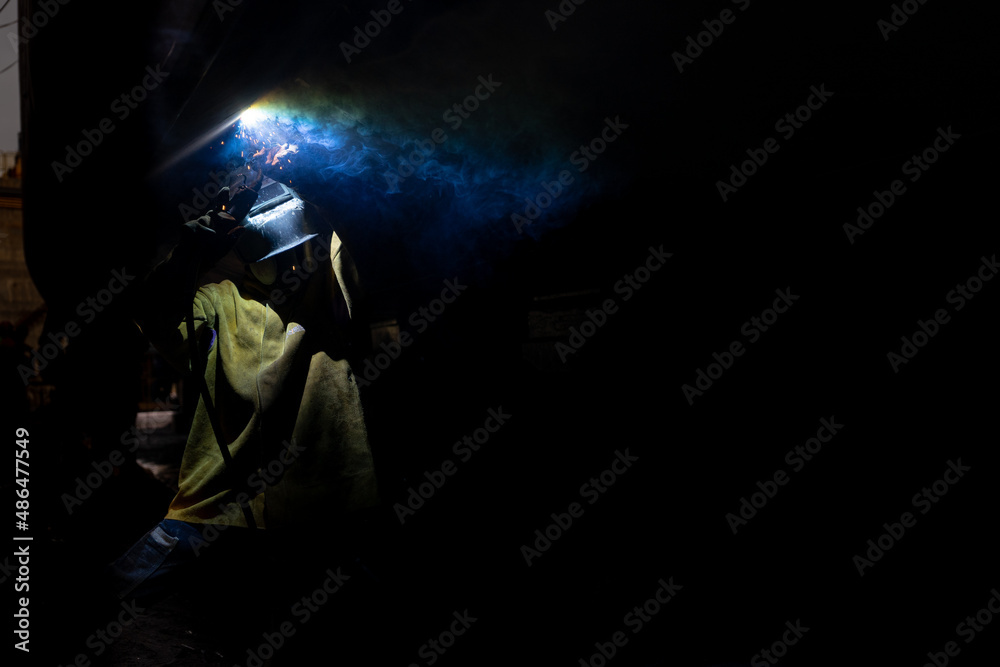 Welder welding a ship at a shipyard Welder welding a ship at a shipyard