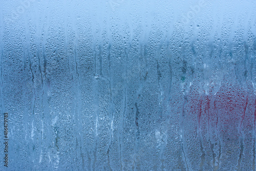 Water droplets condensation background of dew on glass, humidity and foggy blank background. Condensation on the glass of metal-plastic window. Outside the window, bad weather, rain © Aleksandr