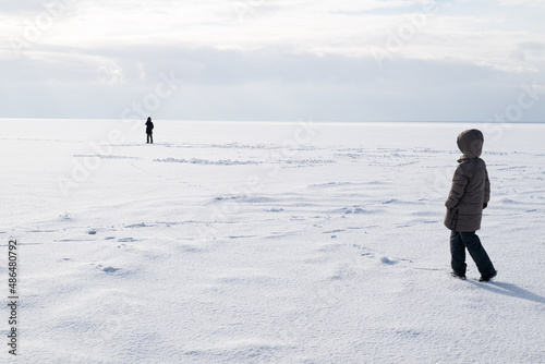 Children are walking on a frozen, snowy river. Winter walk.