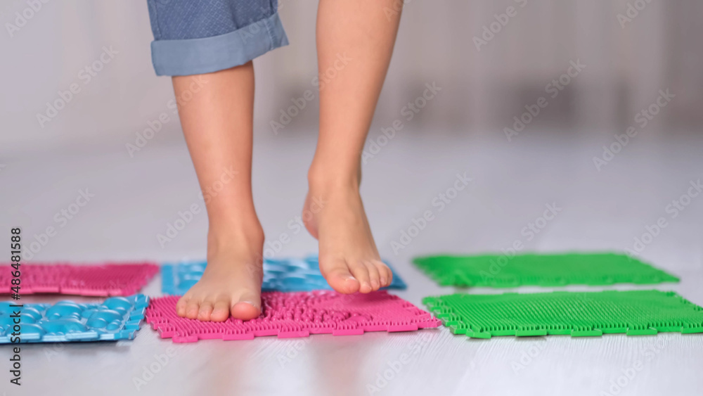 Little boy steps on orthopedic massage mats with different stiffness and texture. Feet Massage Using Trigger Point Spiky Massage Ball. Myofascial Release. close up.