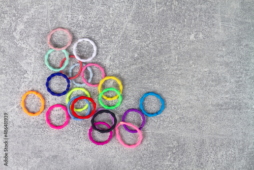 Multicolored elastic bands for hair are scattered on a gray background