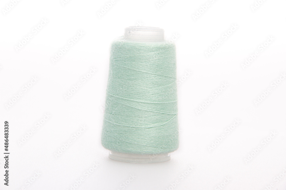 Green spool of thread isolated on white background. Skein of woolen threads. Yarn for knitting. Materials for sewing machine. Coil Green spool of thread isolated on white background. Skein of woolen threads. Yarn for knitting. Materials for sewing machine. Coil
