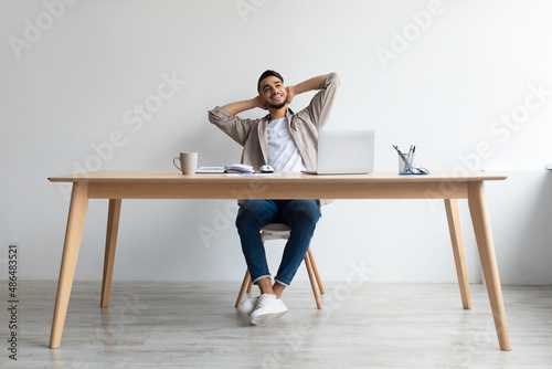 Smiling Arab man leaning back sitting at desk