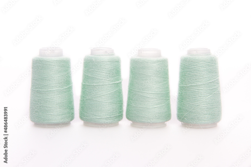 Green spool of thread isolated on white background. Skein of woolen threads. Yarn for knitting. Materials for sewing machine. Coil Green spool of thread isolated on white background. Skein of woolen threads. Yarn for knitting. Materials for sewing machine. Coil