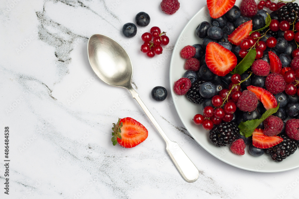 Summer berries salad. Plate of healthy fresh fruit salad: strawberry, blackberry, red currants, blueberry on white marble background. Summer berries salad. Plate of healthy fresh fruit salad: strawberry, blackberry, red currants, blueberry on white marble background.