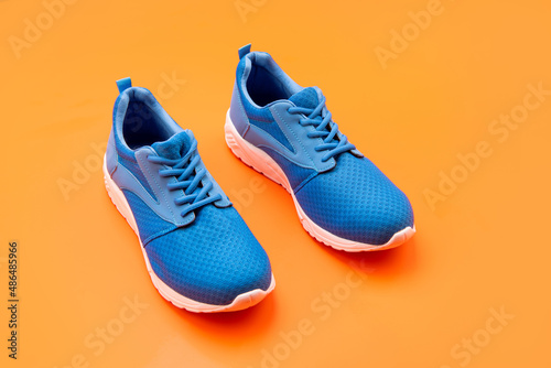 sporty blue sneakers pair on orange background, sport