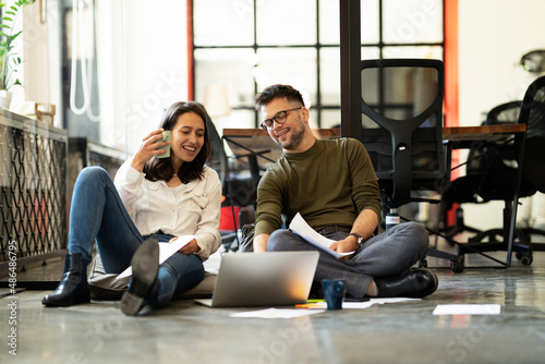 Colleagues in office. Businesswoman and businessman sitting on the floor. Colleagues working on the project.