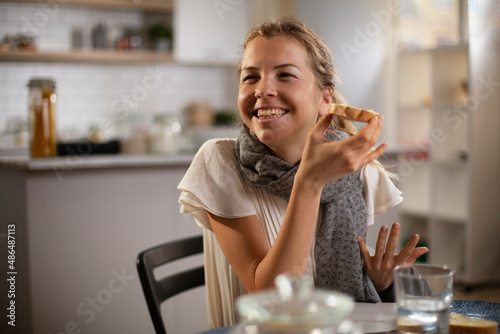 Beautiful woman enjoying in breakfast. Happy young woman eating sandwich at home..