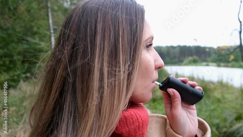 A young woman smokes GLO. device for smoking electronic tobacco heating system. Woman smokes GLO photo