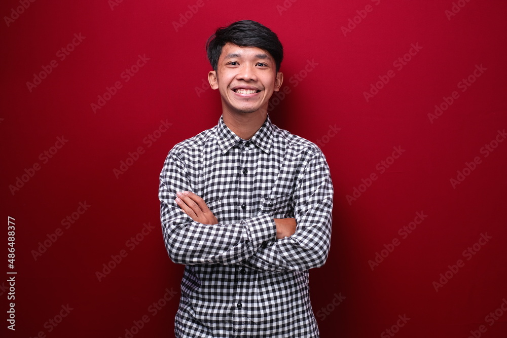 Young handsome man wearing casual shirt over red background happy face smiling with crossed arms looking at the camera. positive person. Young handsome man wearing casual shirt over red background happy face smiling with crossed arms looking at the camera. positive person.